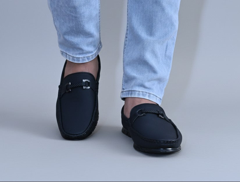 Black ZAWA Monarcha loafers worn with light blue jeans on a neutral background