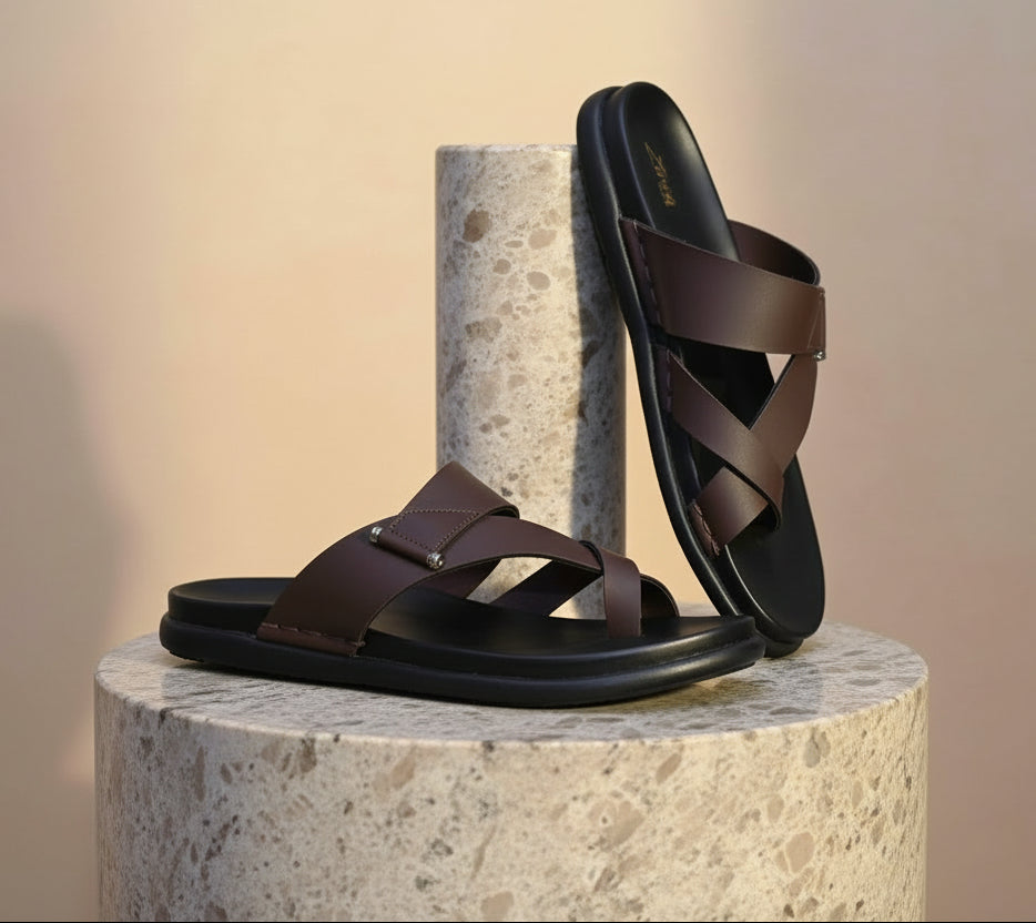Black zawa cruze sandal with brown straps on a marble platform.