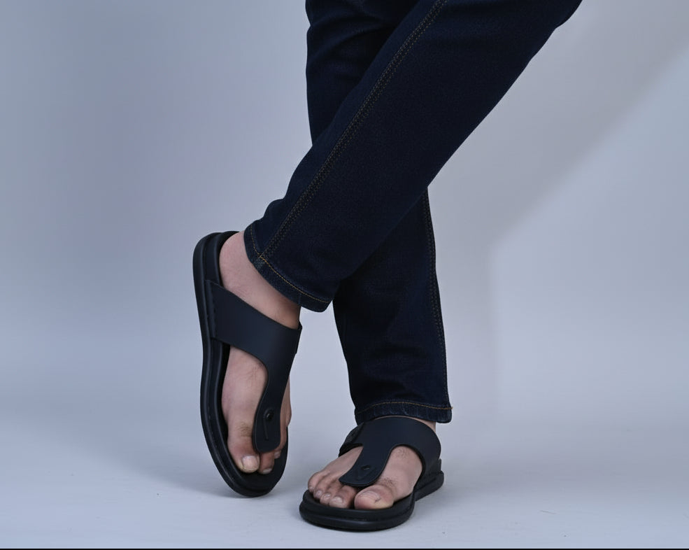 Person wearing ZAWA RIVANO black sandals and light blue jeans against a plain background
