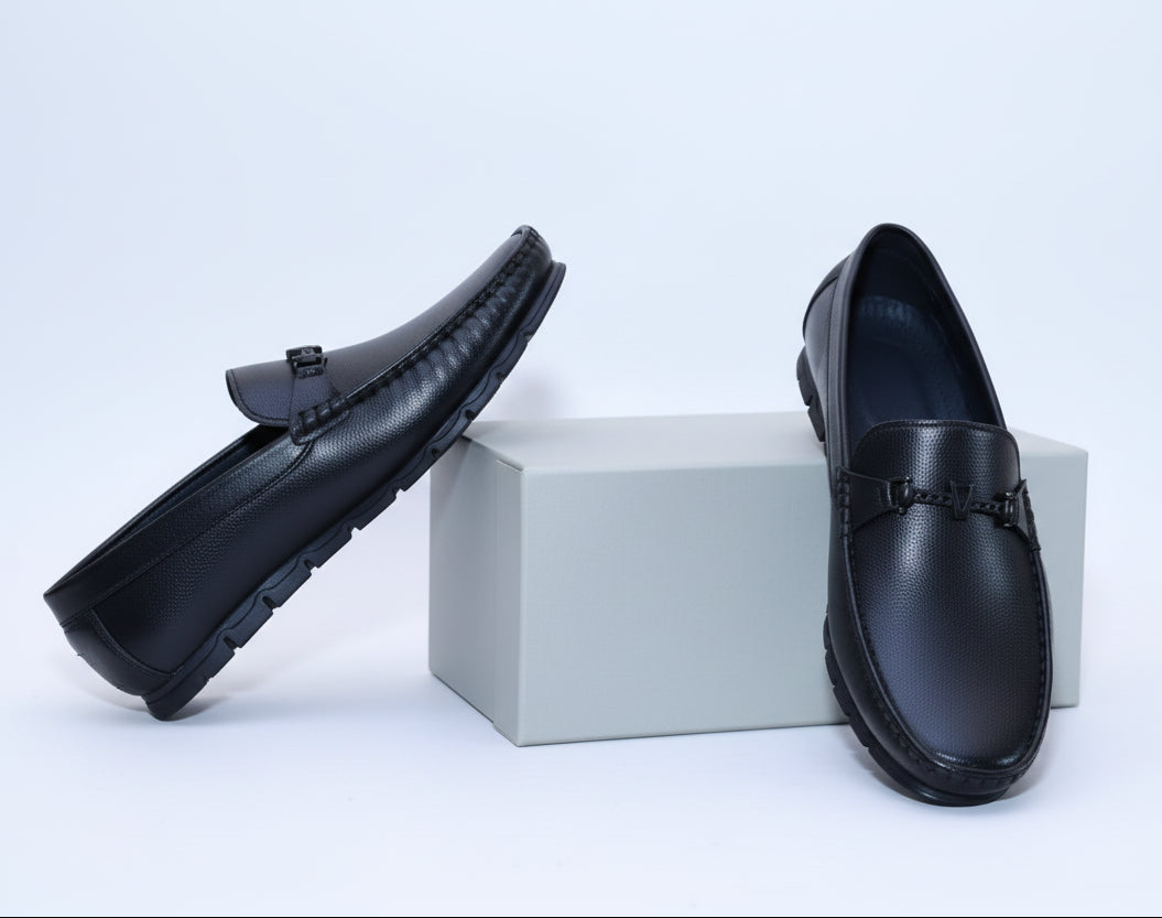 Pair of Zawa Valoris black loafers on a plain surface with a grey box in the background.