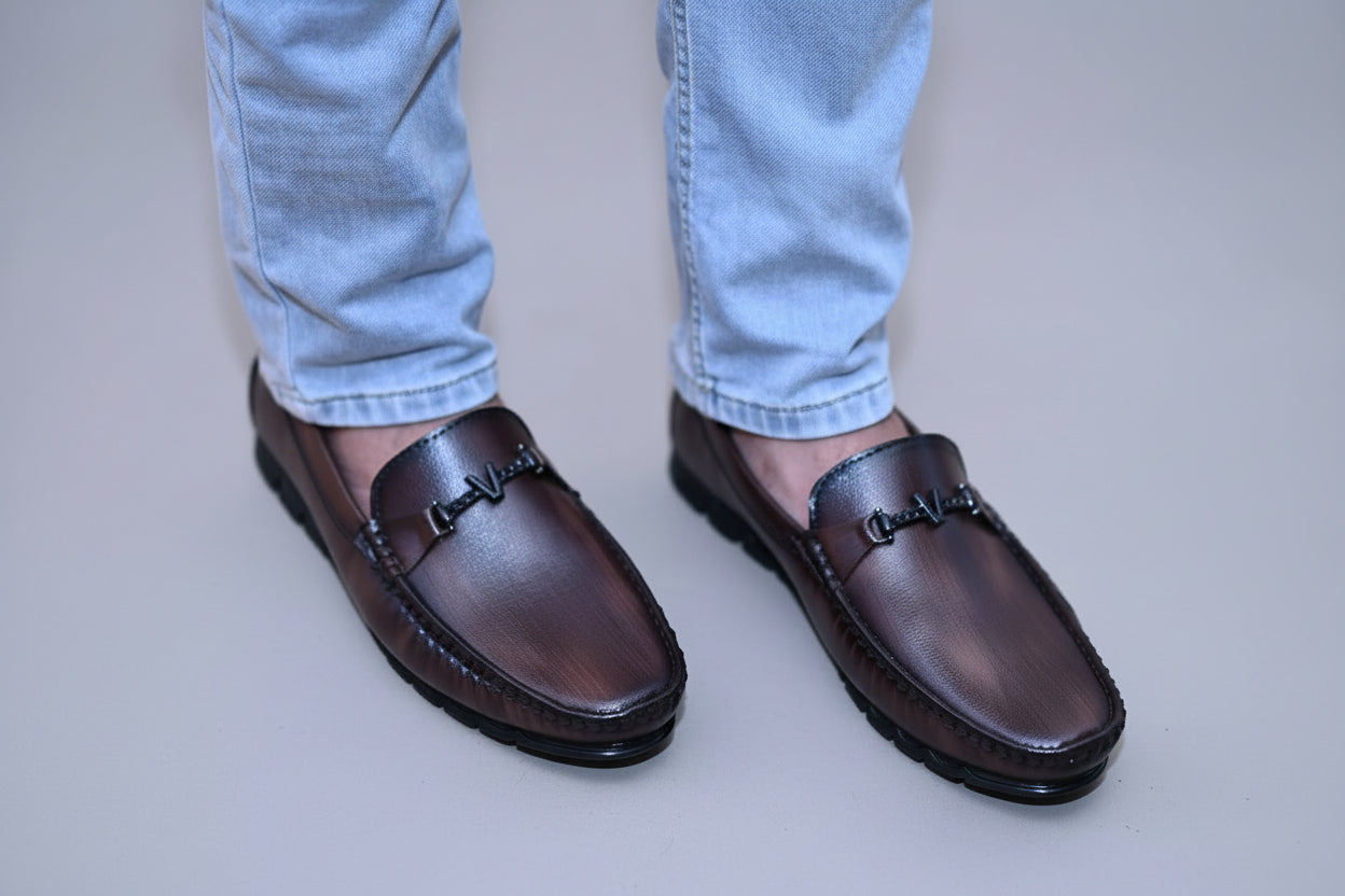 ZAWA Valoris Brown loafers worn with light blue jeans on a plain bakground