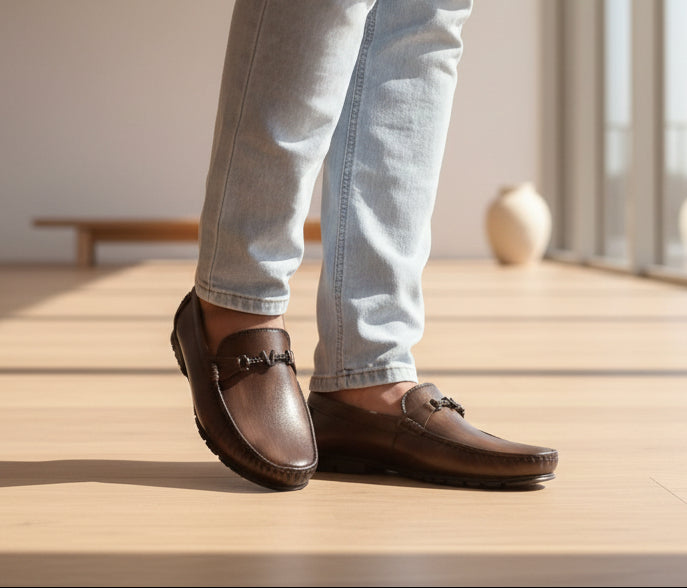 Zawa valoris Brown loafers worn with light blue jeans on a wooden floor.