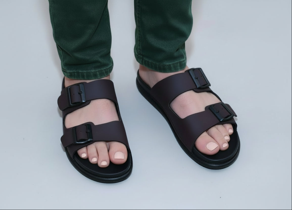 Person wearing zawa vereno brown sandals with buckles on a wooden floor