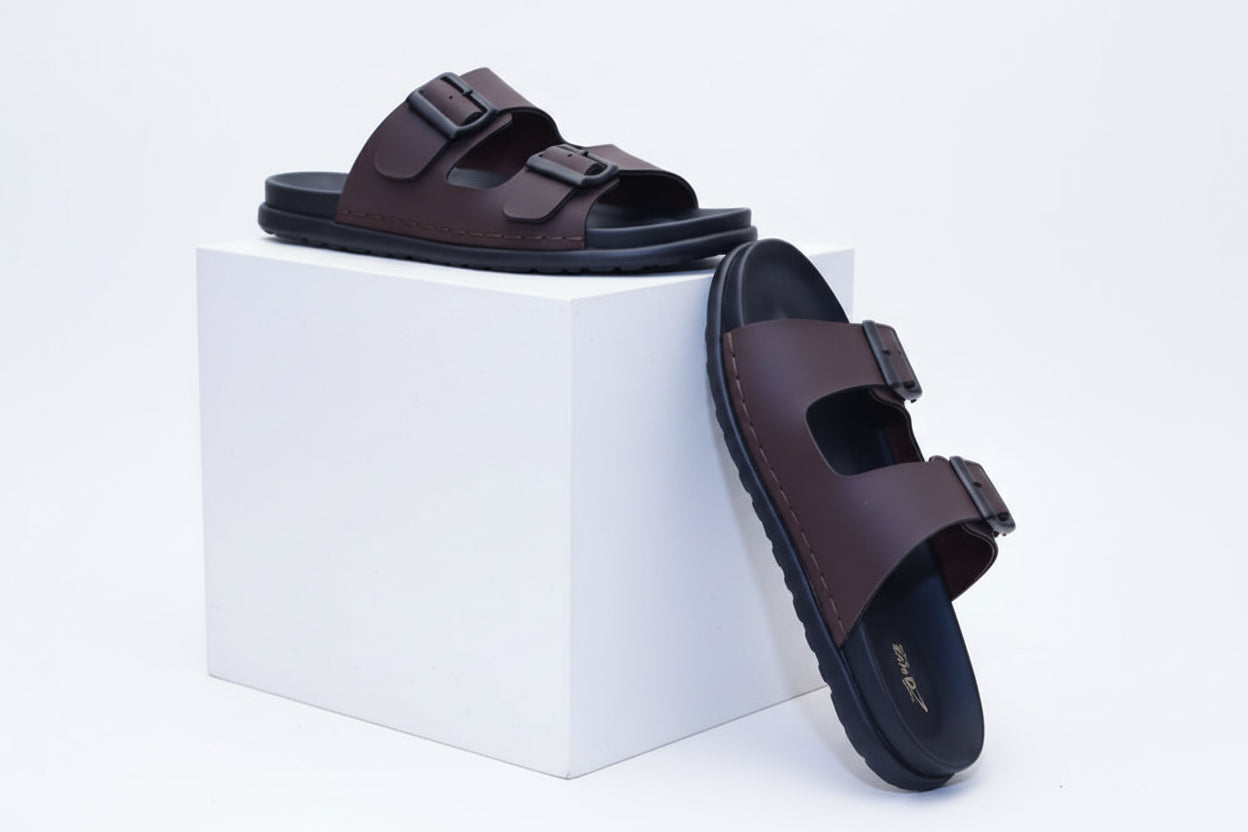 Pair of dark brown sandals placed and leaned against a white cube box