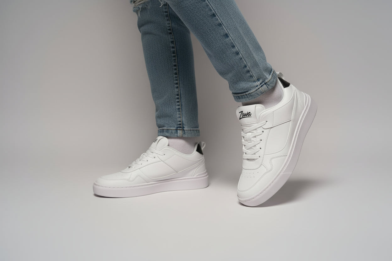 White sneakers with Zawa brand logo worn with light blue jeans on a neutral background