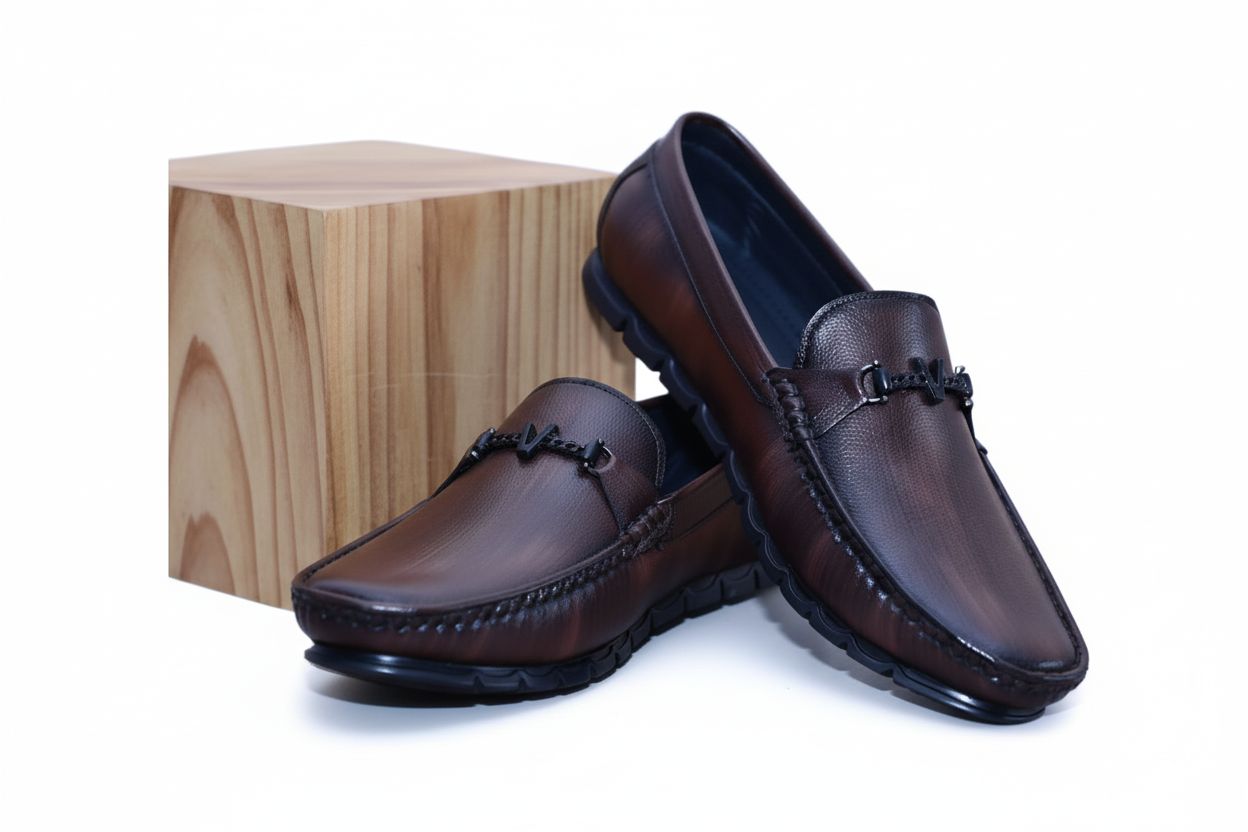 Pair of brown leather zawa loafers on a wooden block with a white background