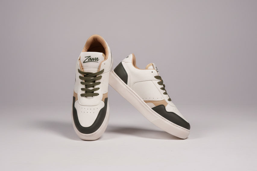 White sneakers with white soles and green laces on a grey background