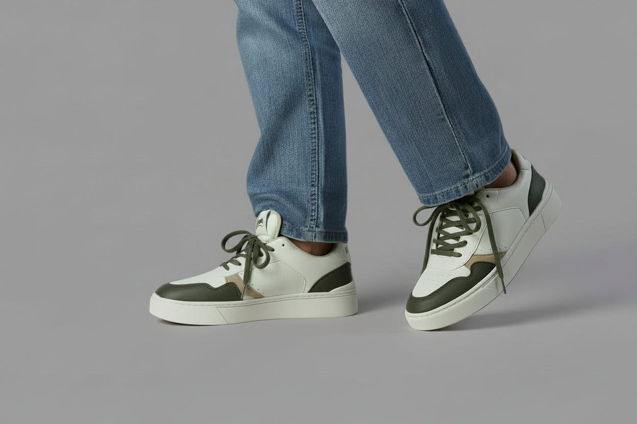 White zawa sneakers with green accents worn by a person sitting on a chair